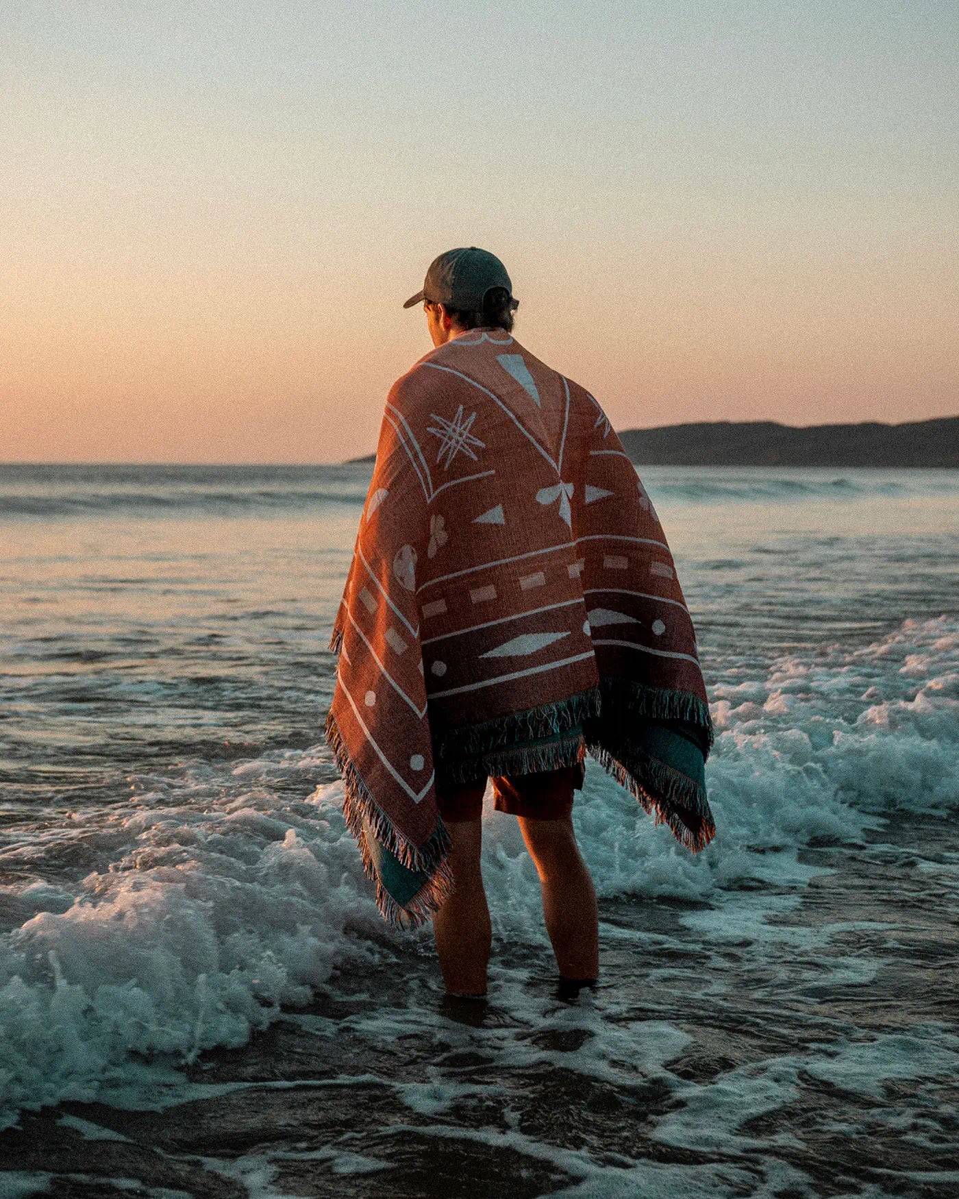 Man wearing a Rug Lord woven picnic throw at the beach during golden hour